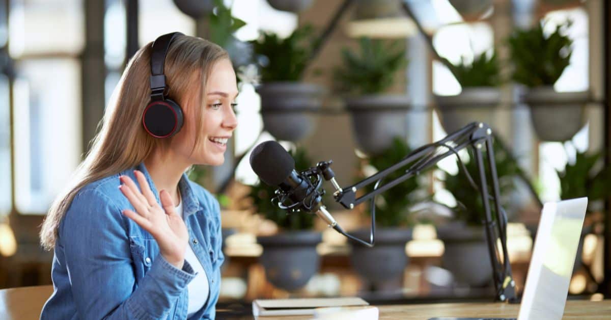 best podcast for bloggers - happy woman with headset, microphone, and laptop