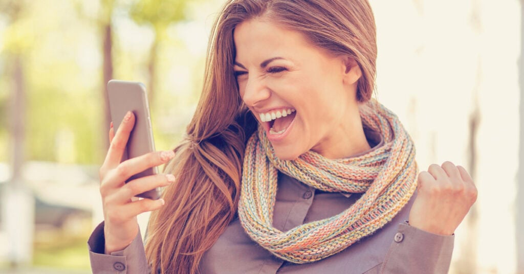 excited woman holding her phone - how to make money from you phone