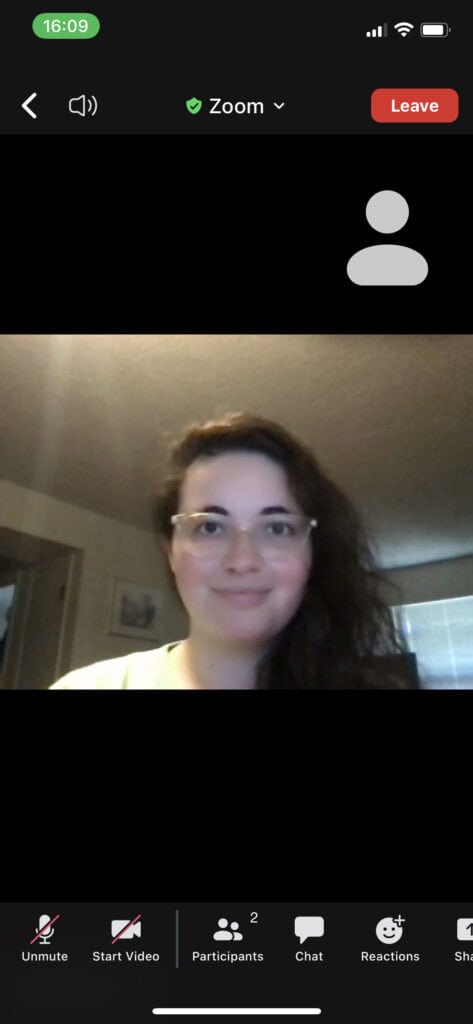 mobile screenshot of zoom meeting with woman smiling and bottom toolbar visible